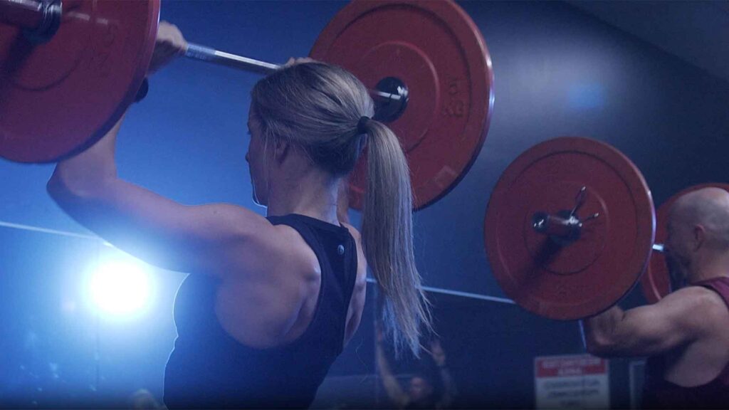 woman lifting weights over her head in the gym